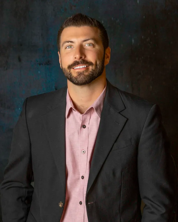 Man in black suit jacket and pink shirt