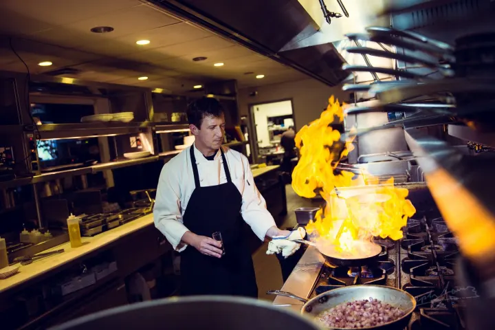 Chef cooking with flames in kitchen