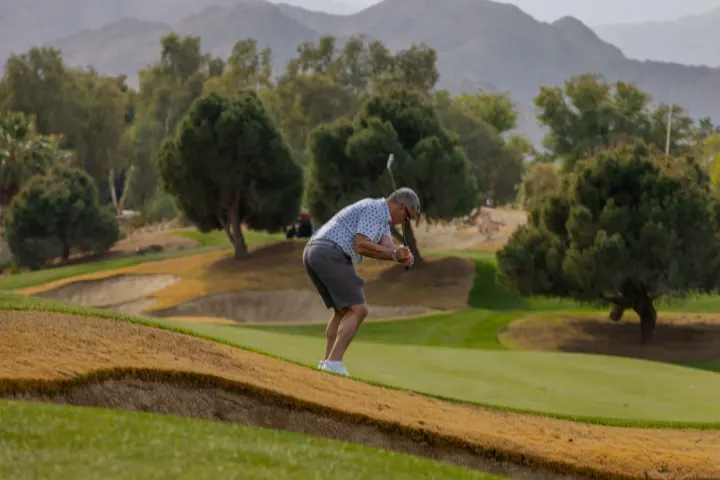 Golfer swinging on grassy hill