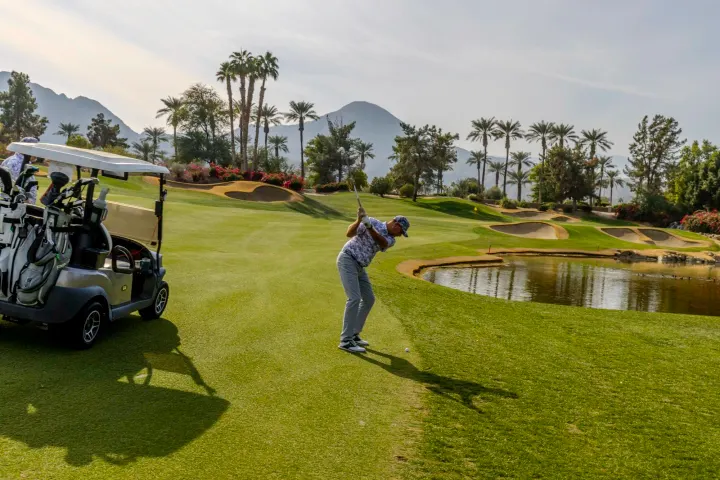 Golfer near water on green course
